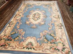 a blue and beige rug with flowers on it