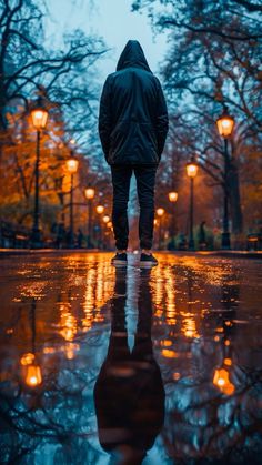 a person standing in the rain with their back turned to the camera and lights on