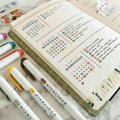 several pens are lined up next to an open notebook