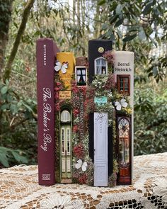 there are many books stacked on top of each other in front of some trees and bushes