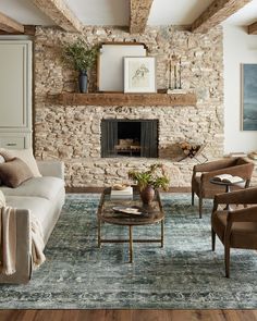 a living room filled with furniture and a fire place in front of a stone wall