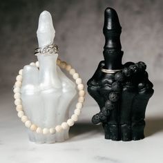 two black and white bottles with beads on them, one has a ring in it's mouth