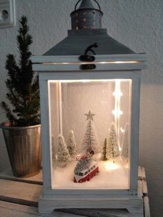 a small christmas scene in a lantern with trees and a train on the tracks inside