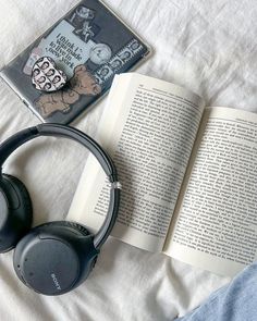 an open book and headphones on top of a bed