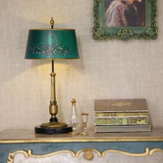 a green lamp sitting on top of a table next to a book and two books