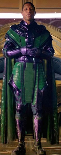 a man dressed in green and purple standing with his arms crossed