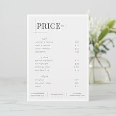 a price card sitting on top of a table next to a vase filled with flowers