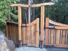 two wooden gates with numbers on them are open in front of some rocks and trees