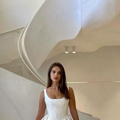 a woman in a white dress is walking down the stairs