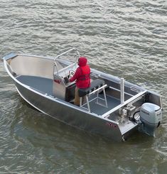 a man sitting in the back of a silver boat on top of a body of water