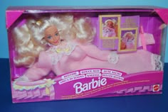 a pink barbie doll in its box on a blue surface