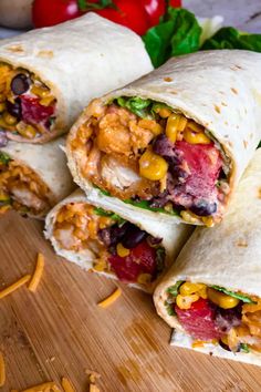 several burritos on a wooden cutting board with cheese and vegetables in the wrapper