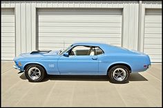 a blue muscle car parked in front of a garage