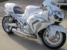 a white motorcycle parked on top of a sidewalk