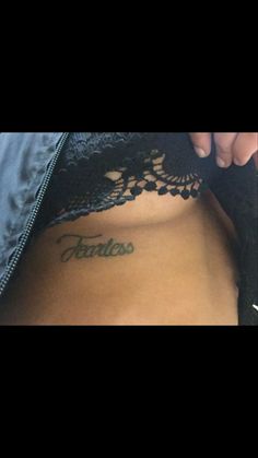 a woman with tattoos on her stomach and the word fearless written in cursive writing