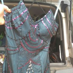 a woman's hand is holding up a dress in the back of a car