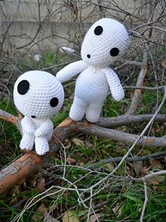 two white stuffed animals sitting on top of a tree branch