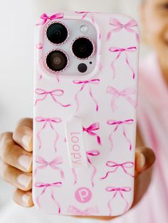 a person holding up a cell phone case with pink bows on it and two buttons