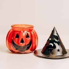 two halloween pumpkin shaped candles sitting next to each other on top of a white table