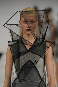 a model walks down the runway in a mesh dress