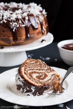 a bundt cake with chocolate icing and coconut on top is sitting on a white plate