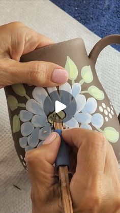 someone is painting a flower on a coffee mug