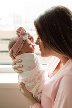 a woman holding a baby in her arms and looking out the window at the city