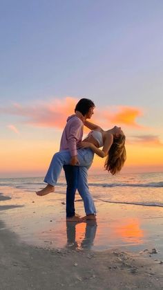 a man and woman are dancing on the beach at sunset with their arms around each other