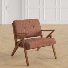 a red chair sitting on top of a hard wood floor next to a white wall