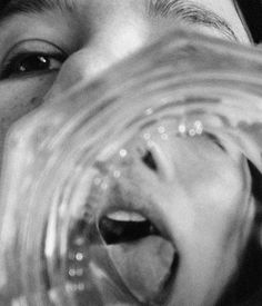 a close up of a person holding a glass in front of their face with an open mouth