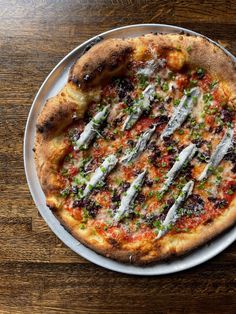 a pizza sitting on top of a white plate covered in cheese and veggies