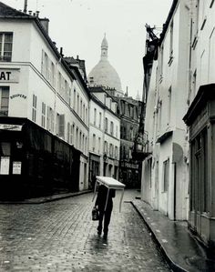 black and white photograph of two people walking down the street with an umbrella over their heads