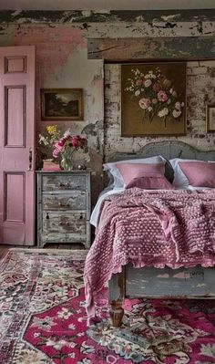 a bedroom decorated in pink and white with an old bed, dressers, rug and painting on the wall