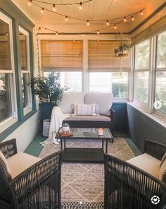 a screened porch with wicker furniture and string lights