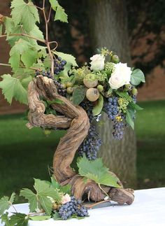 a vase filled with flowers and vines on top of a table