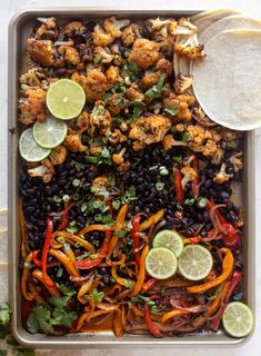 a tray filled with chicken, black beans and limes