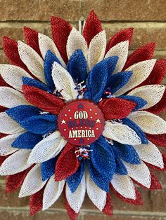 a red, white and blue wreath hanging on a brick wall with the words god made america painted on it