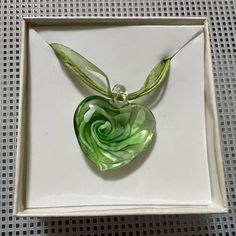 a green heart shaped glass pendant in a white box