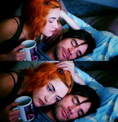 two people laying in bed with one holding a coffee mug