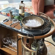 a bar cart with wine glasses and bottles on it