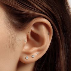 a woman's ear with three small diamond studs on the top of it