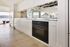 an empty kitchen with white cabinets and black stove top oven in front of a large window