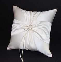 a white pillow with a ring tied to it's side on a black background