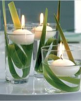 three candles with green leaves in glass vases