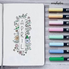 an open notebook with the word april written on it next to some markers and pens