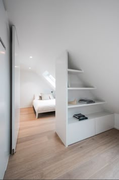 an attic bedroom with white shelving and wooden floors