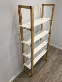 a white shelf sitting in the corner of a room next to a wooden floor and wall