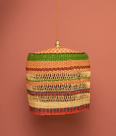 an ornament hanging from a string on a pink wall with red and green stripes