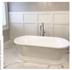 a white bath tub sitting in a bathroom next to a window