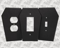 three black wall plates with one light switch plate and the other two are facing each other